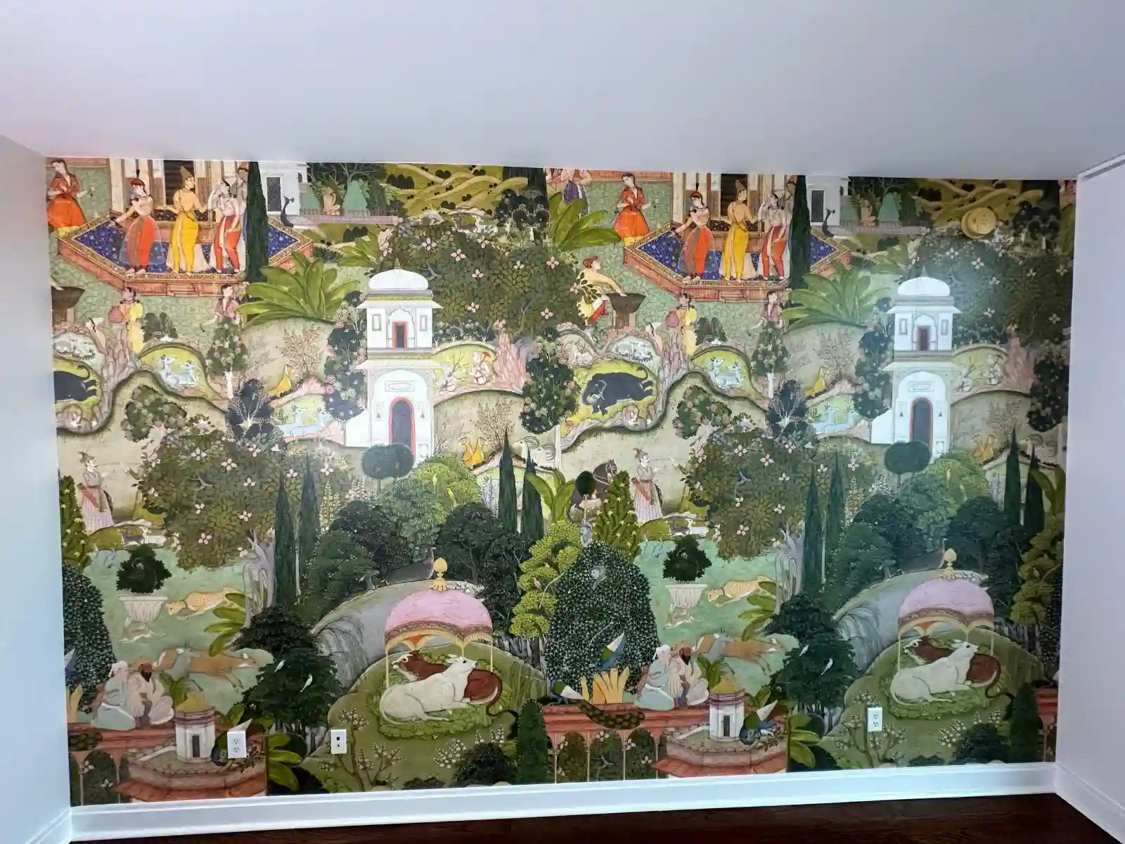 Unfurnished room with a full wall of illustrated garden mural wallpaper and dark wood flooring.